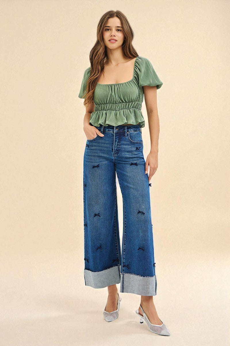 Woman wearing a green top and blue jeans on a beige background