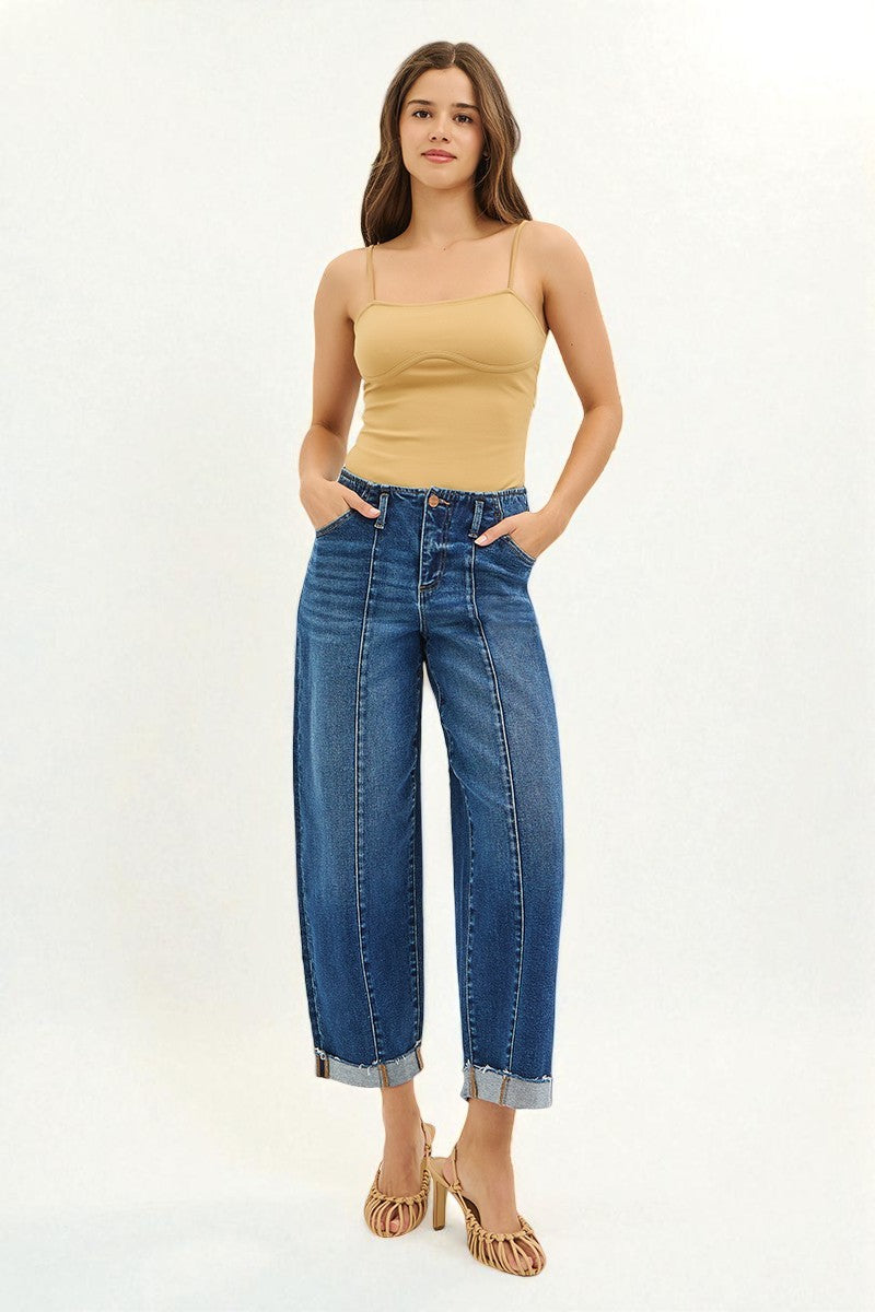 Woman wearing a beige top and blue jeans on a white background