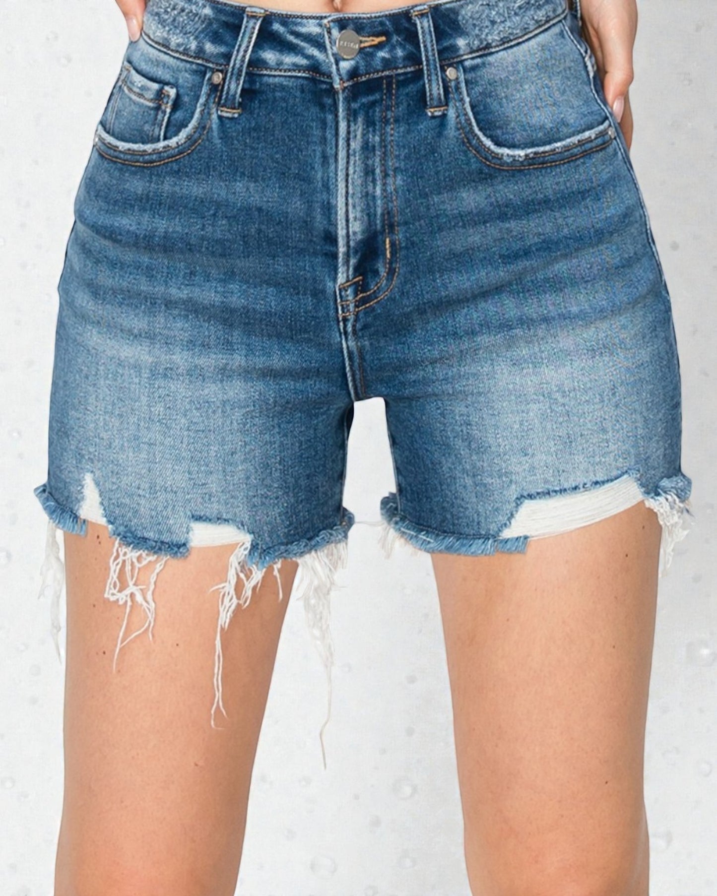 Denim shorts with frayed edges on a plain background