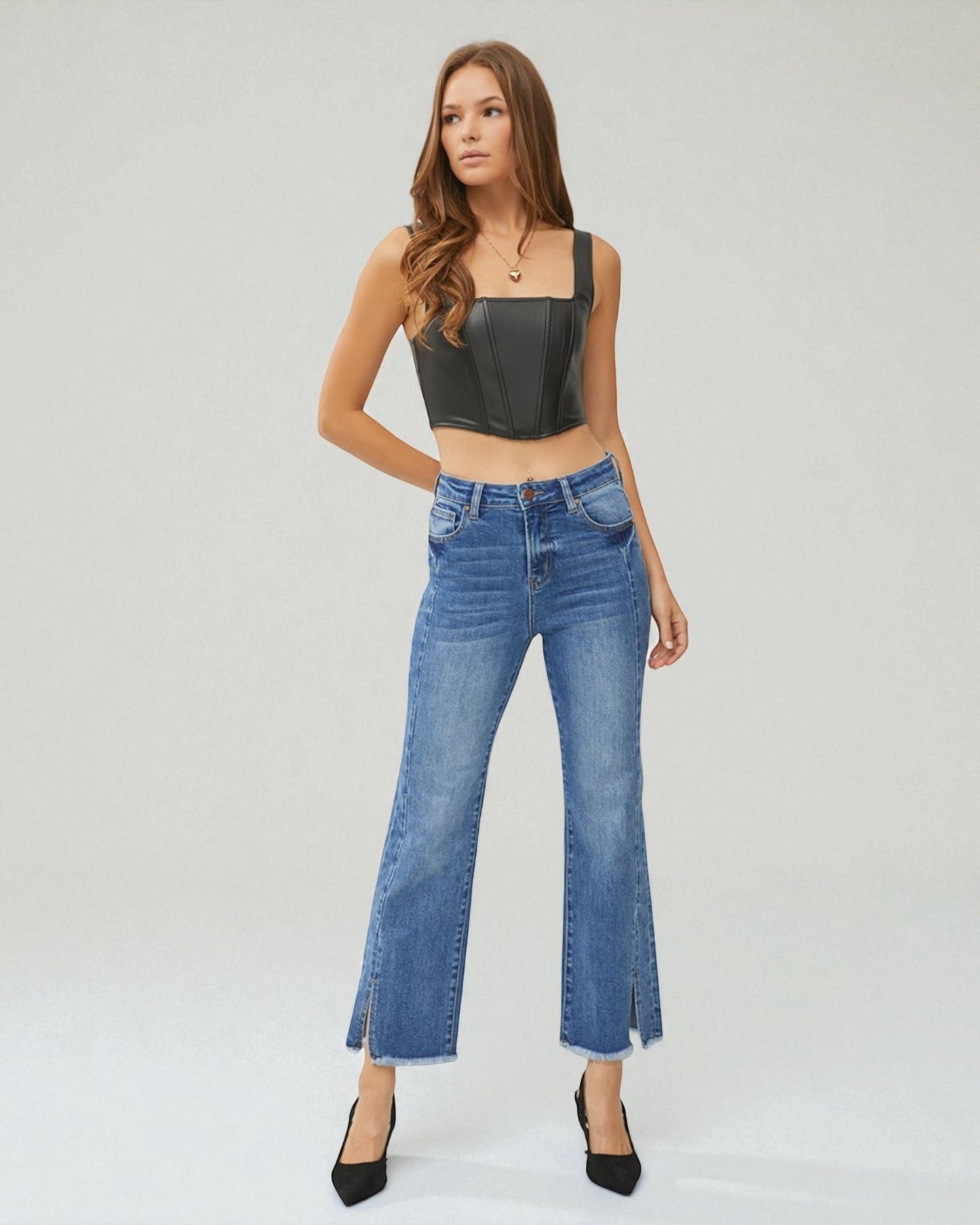 Woman wearing a black leather top and blue jeans on a white background
