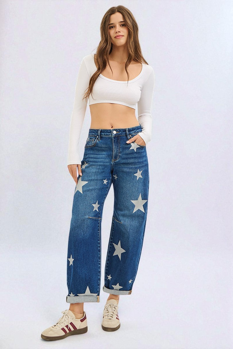 Woman wearing blue jeans with star patterns and a white top on a light gray background