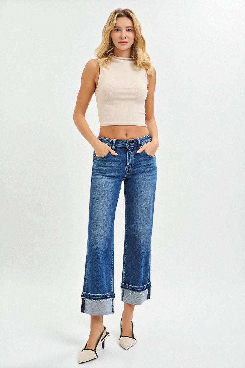 Woman wearing a beige sleeveless top and blue jeans on a white background