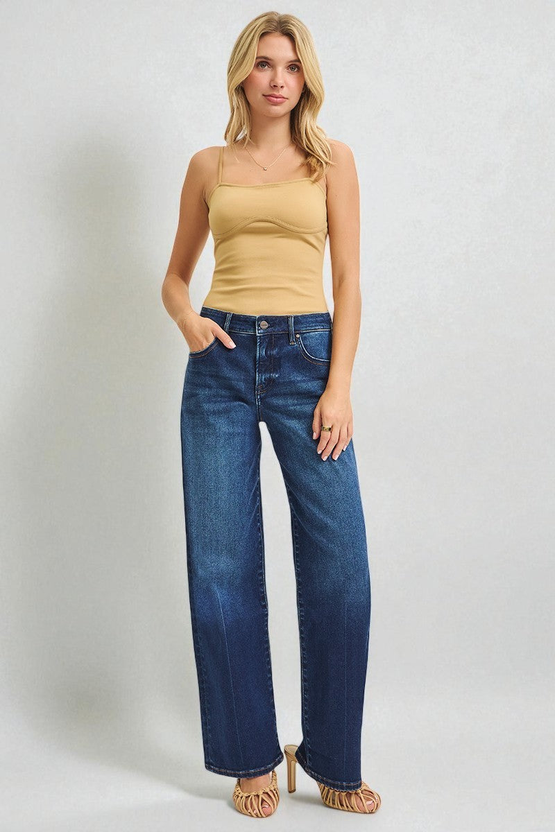 Woman wearing a beige tank top and blue jeans on a white background