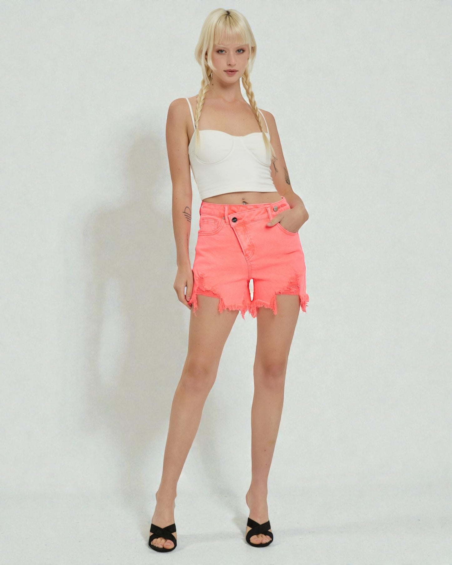 Woman wearing a white top and bright pink shorts on a white background