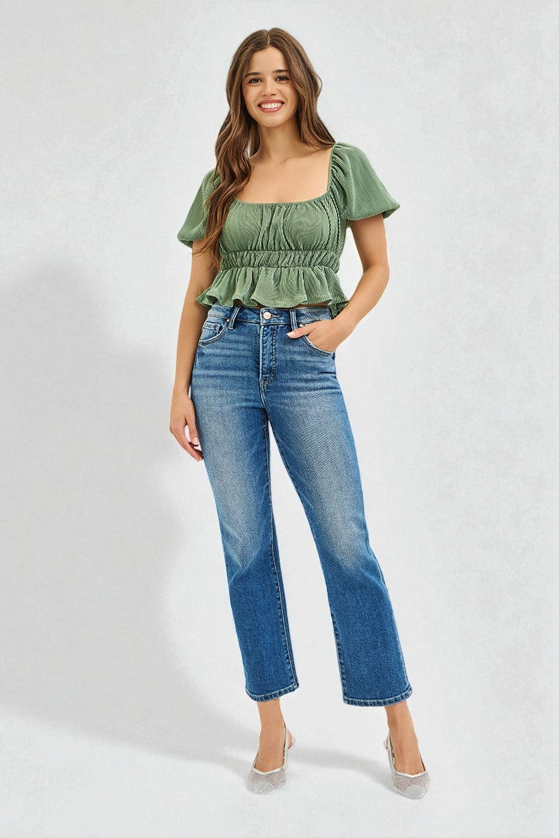 Woman wearing a green top and blue jeans on a white background