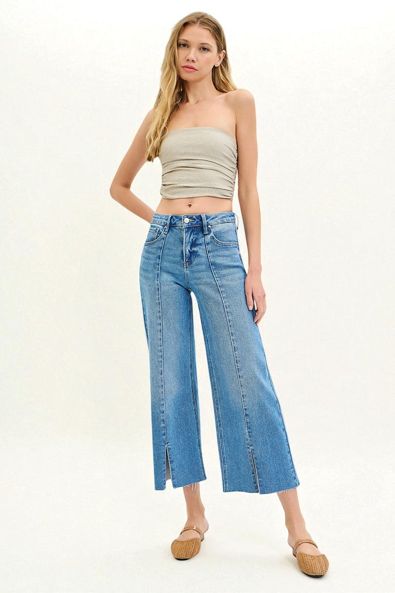 Woman wearing a beige strapless top and blue jeans on a white background