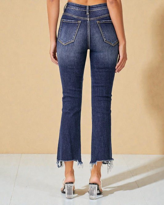 Blue jeans with frayed hem on a beige background