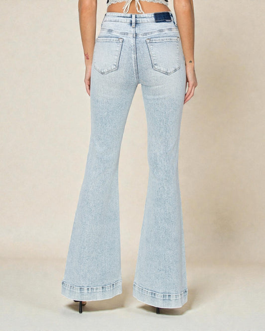 Light blue flared jeans worn by a person on a beige background