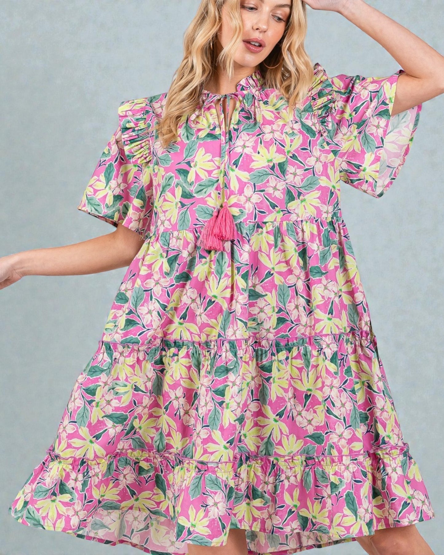 Woman wearing a colorful floral dress against a gray background