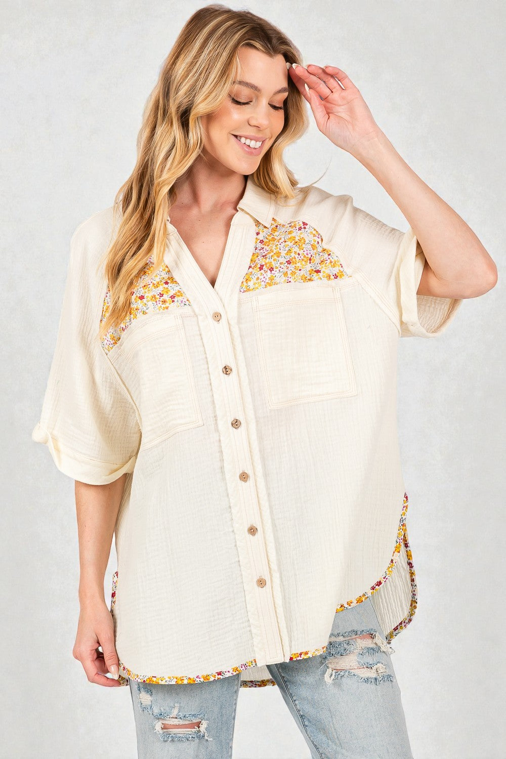 Woman wearing a cream-colored blouse with floral embroidery on a plain background