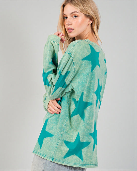 Woman wearing a green cardigan with star patterns on a gray background