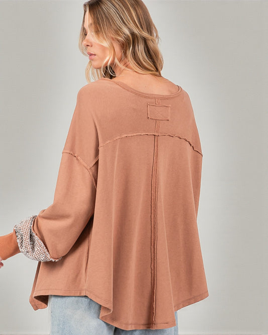 Woman wearing a brown oversized shirt with rolled-up sleeves on a gray background