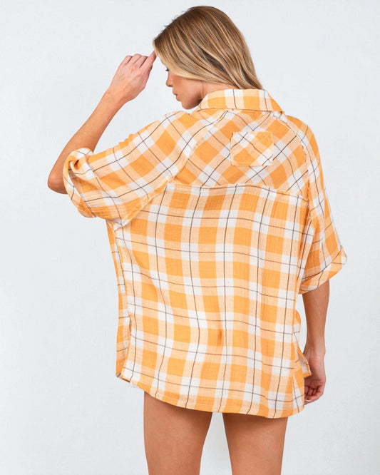 Woman wearing a yellow and white plaid shirt against a plain background