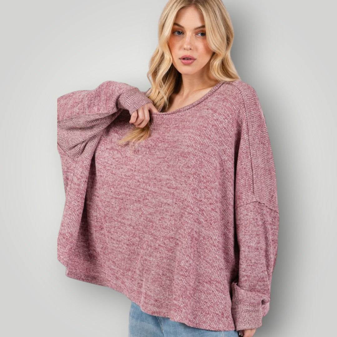 Woman wearing a pink marled sweater against a plain background