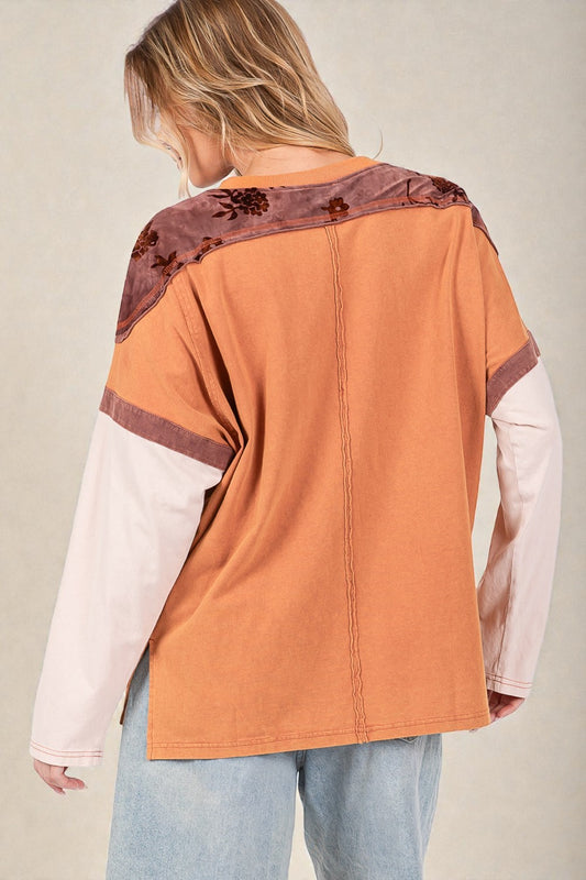 Person wearing a colorful jacket with a patterned shoulder on a neutral background