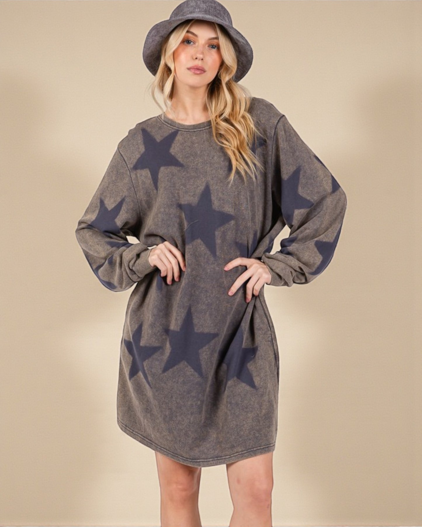 Woman wearing a gray dress with star patterns and a matching hat against a beige background