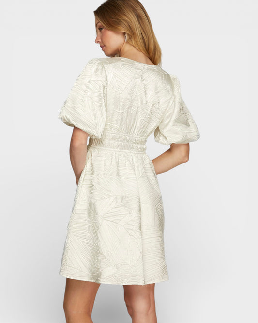 Woman wearing a white dress with puff sleeves on a plain background