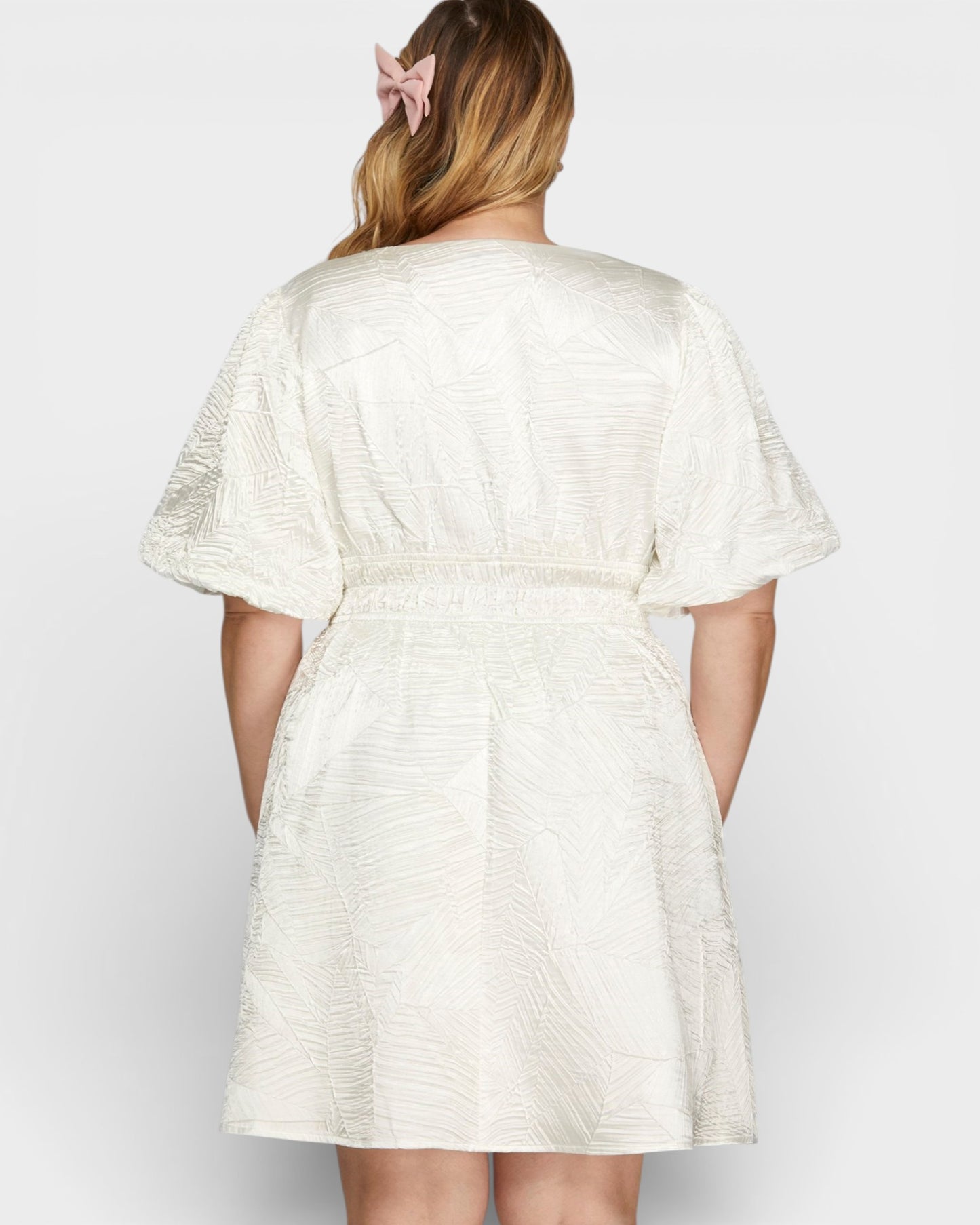 Woman wearing a white textured dress against a plain background