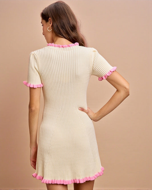 Woman wearing a cream dress with pink trim on a beige background