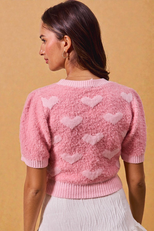 Woman wearing a pink sweater with heart patterns on a beige background