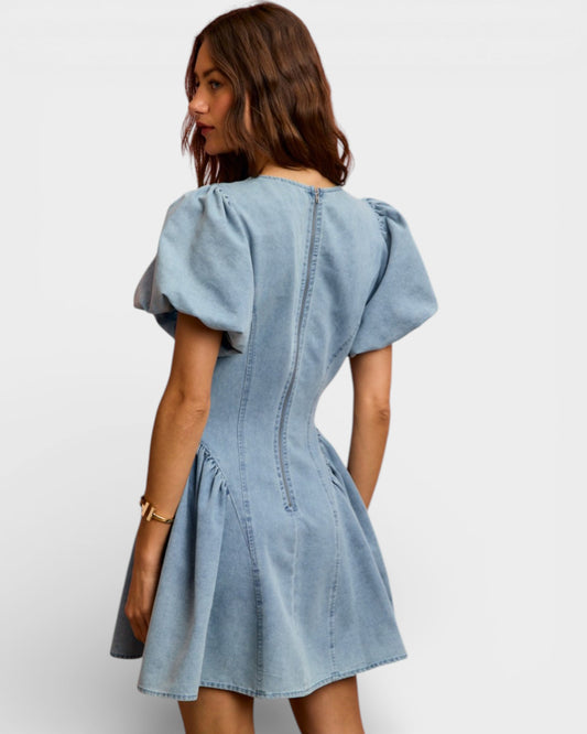 Woman wearing a light blue denim dress on a white background