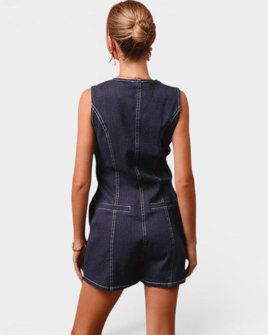Person wearing a dark denim romper on a white background