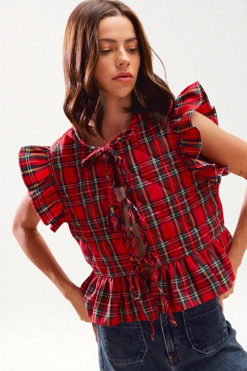 Woman wearing a red plaid top with ruffled sleeves on a white background