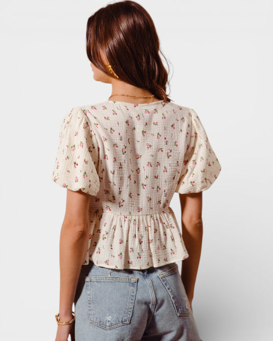 Woman wearing a floral blouse and jeans on a plain background