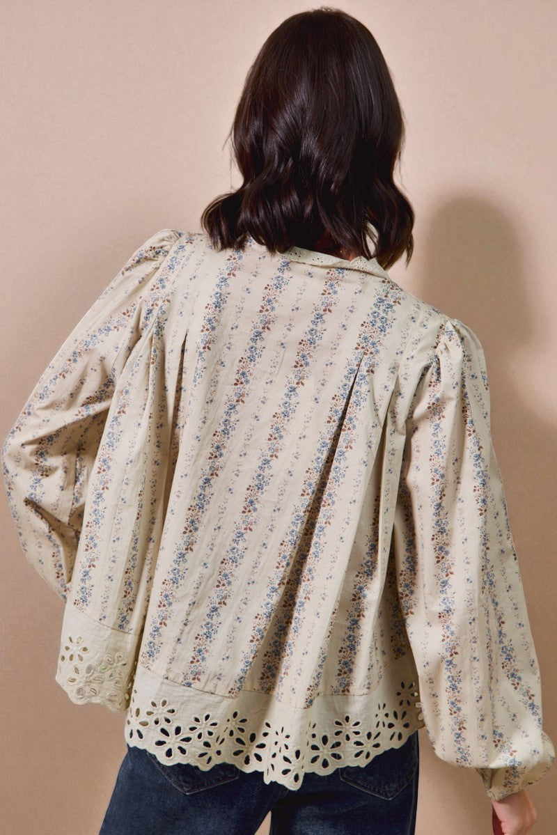 Woman wearing a floral blouse with long sleeves against a beige background