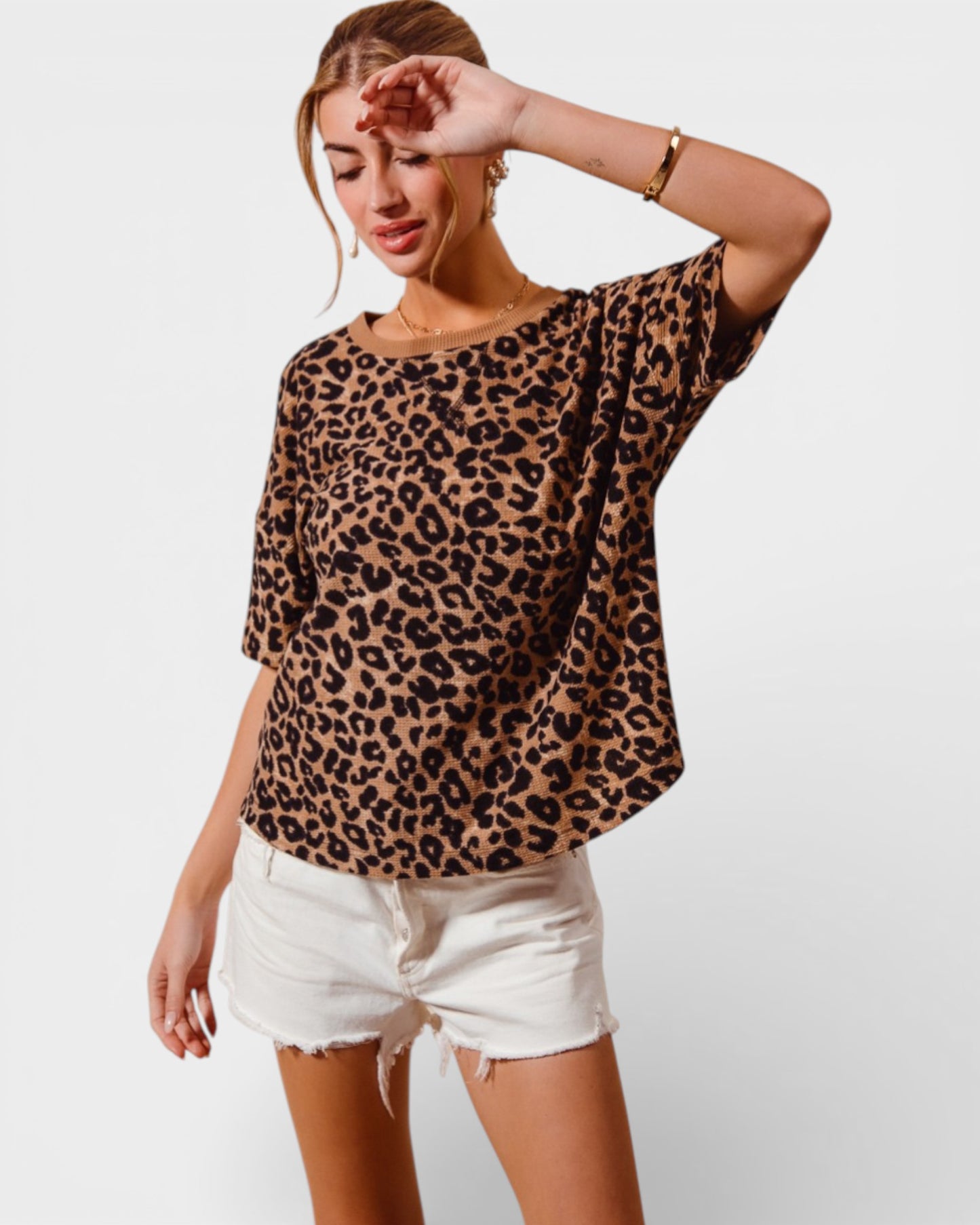 Woman wearing a leopard print top and white shorts on a plain background