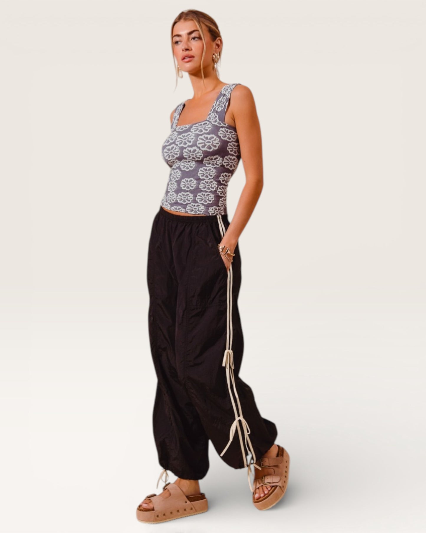 Woman wearing a patterned top and black pants on a white background