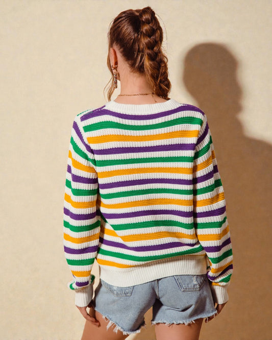 Person wearing a colorful striped sweater against a beige wall