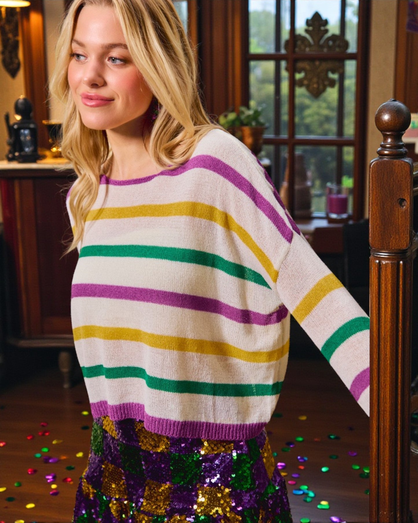 Woman wearing a colorful striped sweater with confetti on the floor