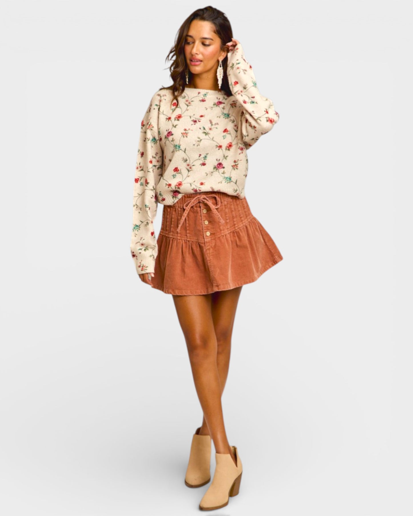 Woman wearing a floral blouse and brown skirt on a white background