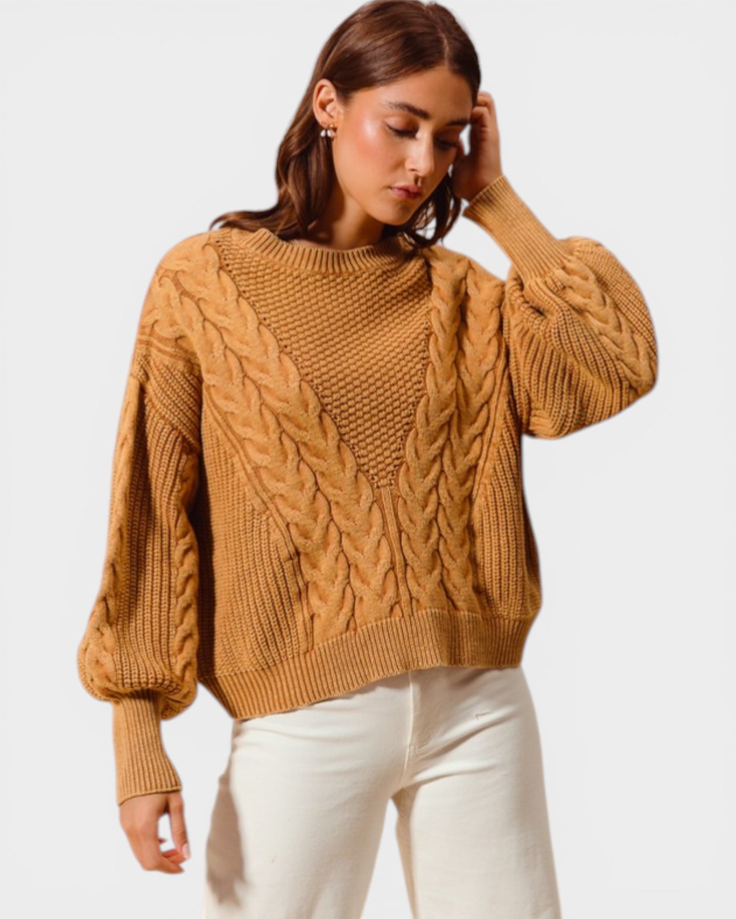 Woman wearing a brown cable knit sweater against a white background