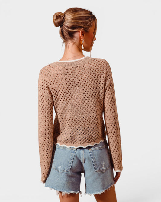 Woman wearing a beige knitted sweater and denim shorts on a white background