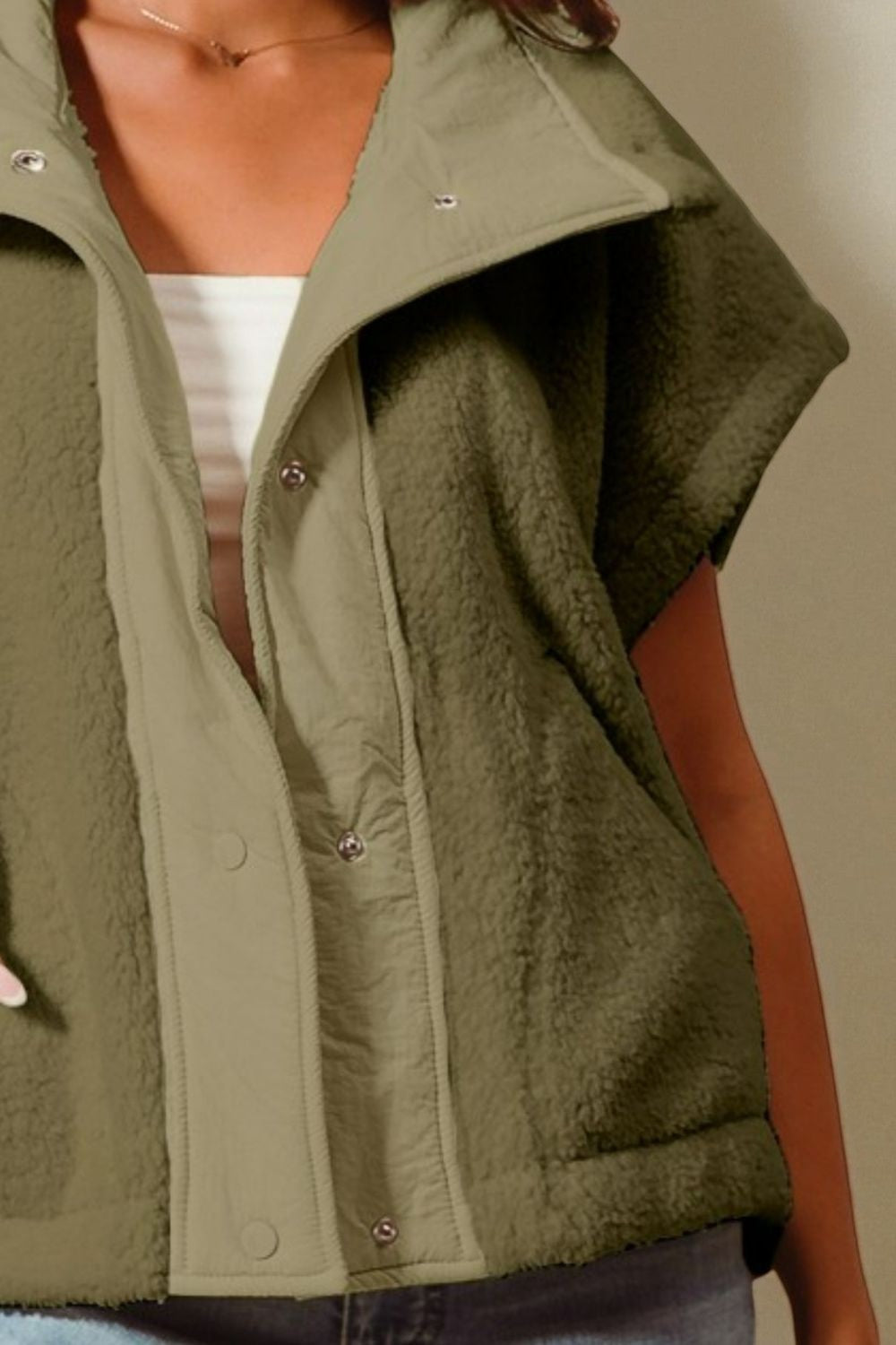 Green vest worn by a person on a plain background