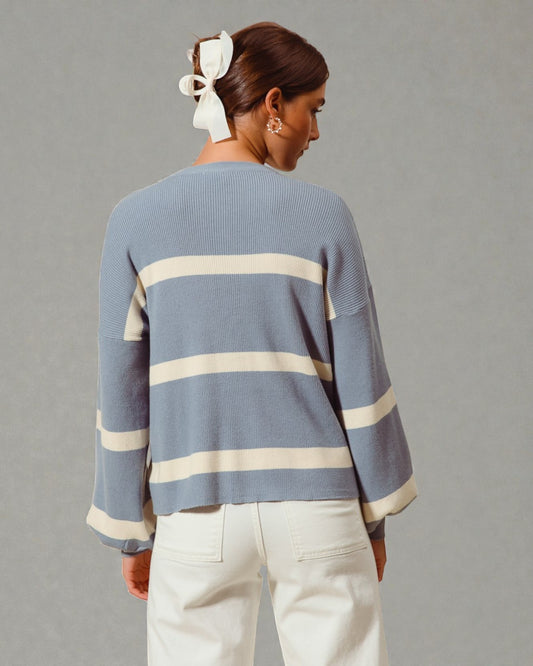 Person wearing a blue sweater with white stripes on a gray background