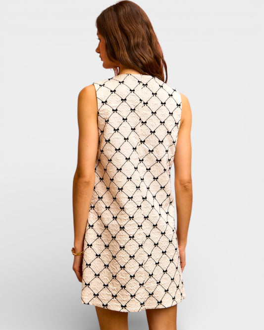 Woman wearing a sleeveless dress with a geometric pattern on a plain background