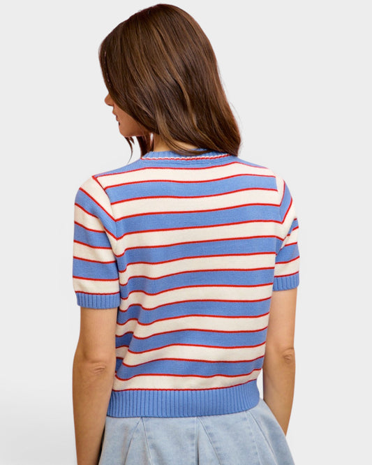 Woman wearing a striped sweater with blue, red, and white colors on a plain background
