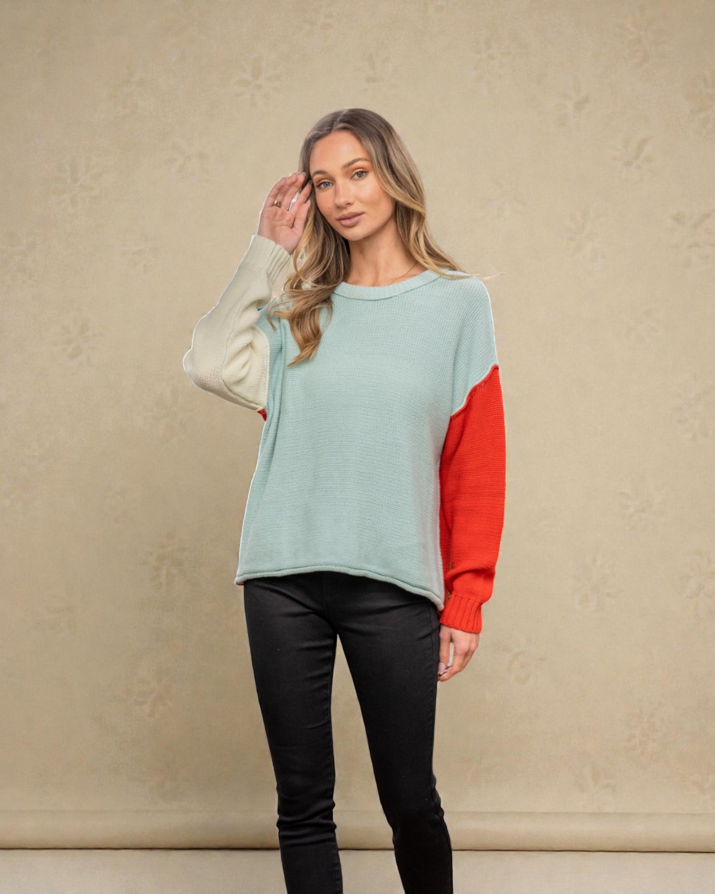 Woman wearing a light blue and red sweater against a beige background