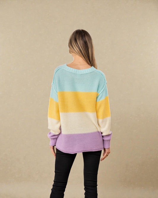 Woman wearing a colorful striped sweater against a beige background