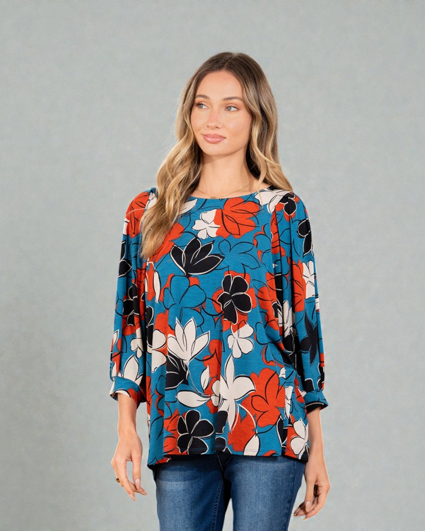 Woman wearing a colorful floral blouse against a gray background