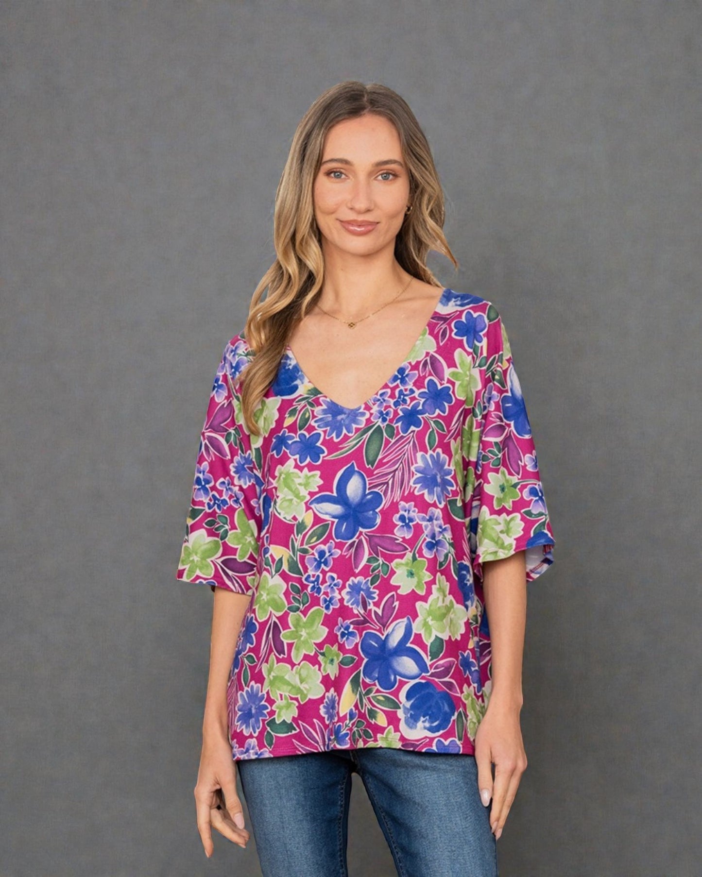 Woman wearing a colorful floral blouse against a gray background