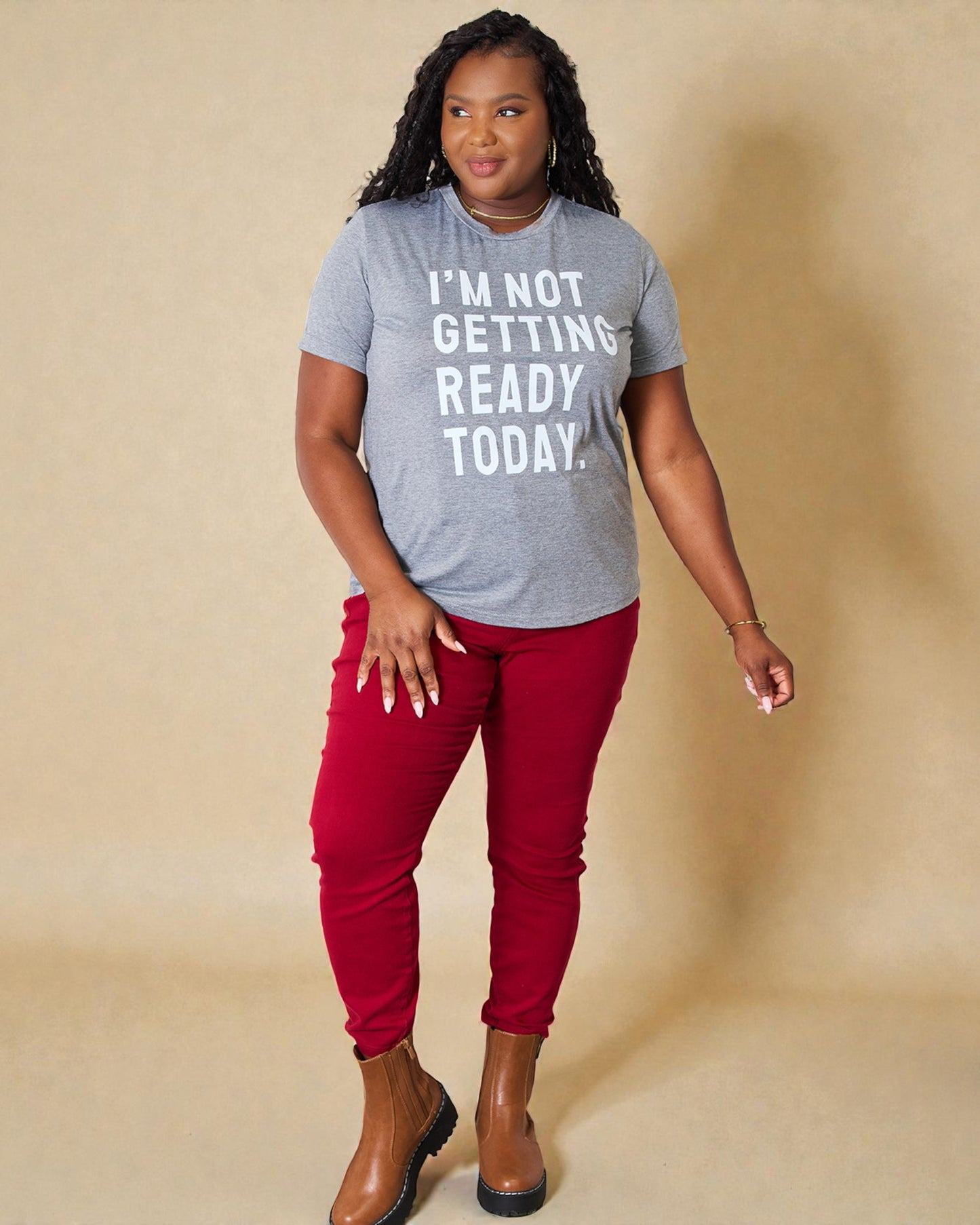 Person wearing a gray t-shirt with text and red pants on a beige background