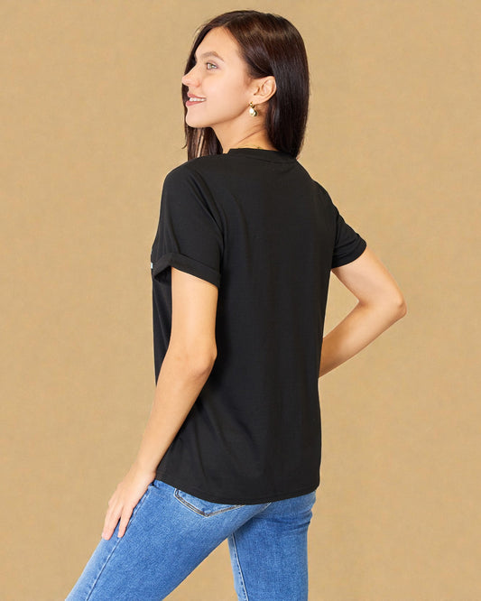 Woman wearing a black t-shirt and blue jeans against a beige background