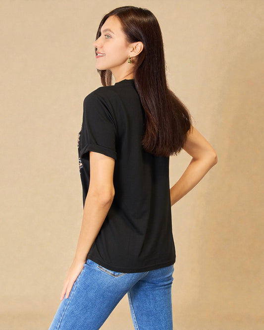 Woman wearing a black t-shirt with text on the back against a beige background