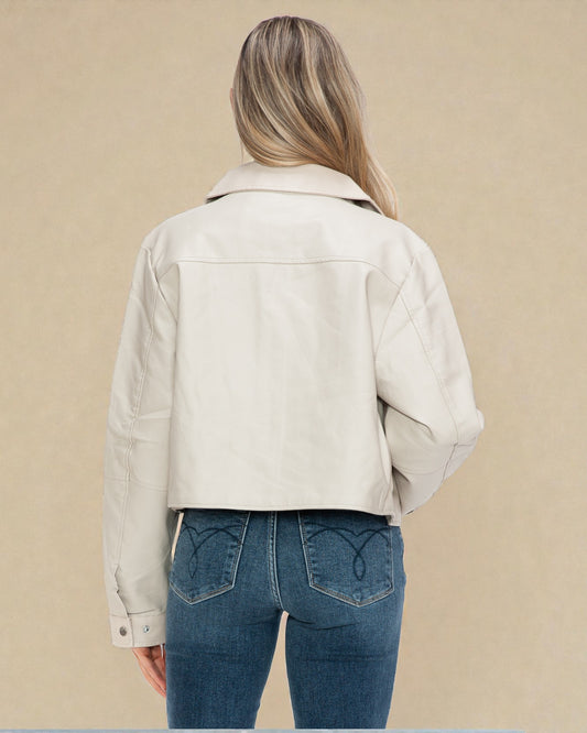 Person wearing a beige jacket and blue jeans on a beige background