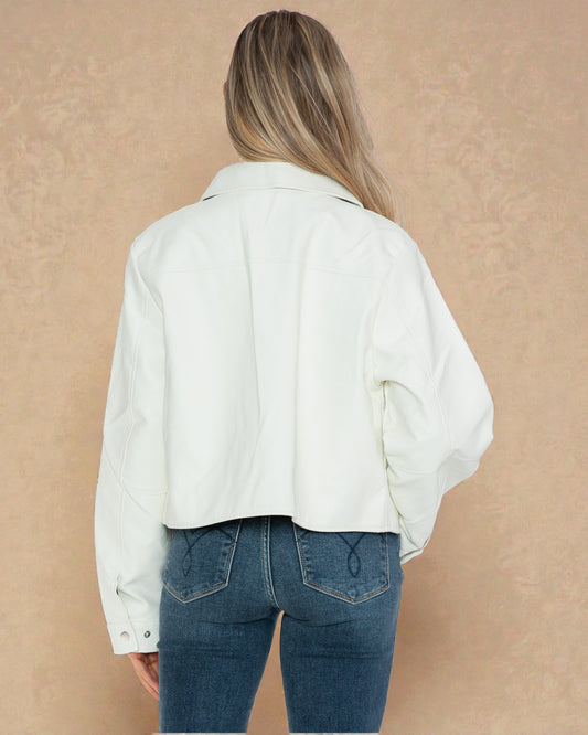 Person wearing a white jacket and blue jeans against a beige background