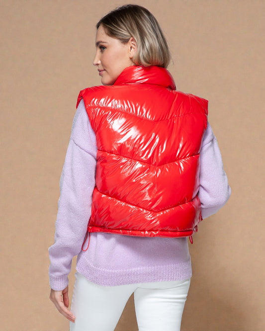 Person wearing a red puffer vest over a light purple sweater on a beige background